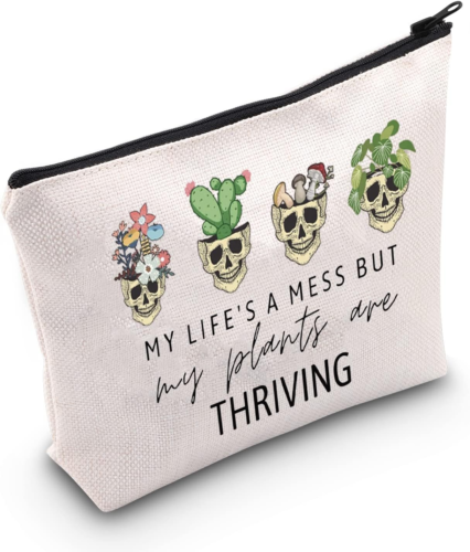 A cosmetic bag with 4 skulls growing different plants inside. It states my life's a mess but my plants are thriving.