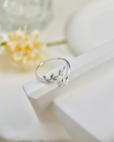 a silver ring shaped like olive leaves on a blurred background