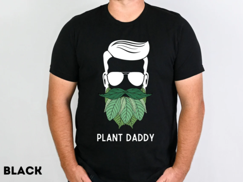 a man wearing a tshirt that reads "plant daddy" with a male face and plant leaves for a beard