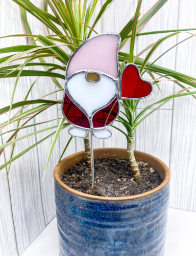 a potted dracaena with a stained glass gnome holding a heart stake